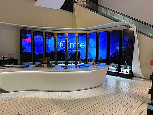 Curved bank of vertical digital display panels installed in a shopping centre retail lounge