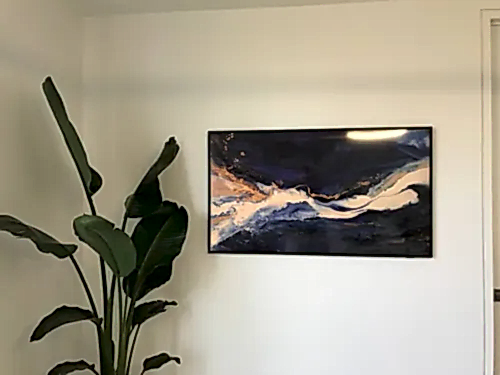 Samsung Frame TV showing an abstract navy and gold canvas on a plain white wall
