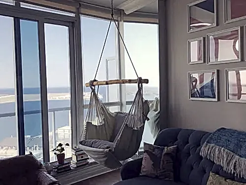 Hanging hammock chair suspended from a condo ceiling beside a gallery wall of framed prints