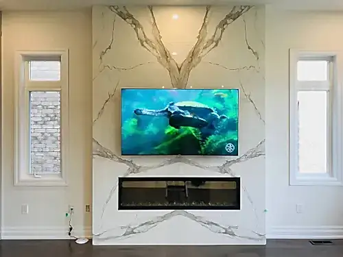 TV mounted on a book-matched marble slab chimney above a linear electric fireplace in a new build