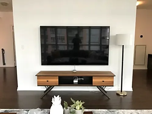 Large flat screen mounted flush on a white wall above a walnut mid-century console