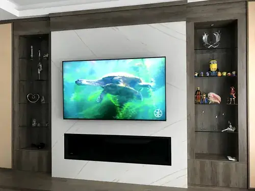 TV mounted on a white marble panel between dark display cabinets, above a linear electric fireplace