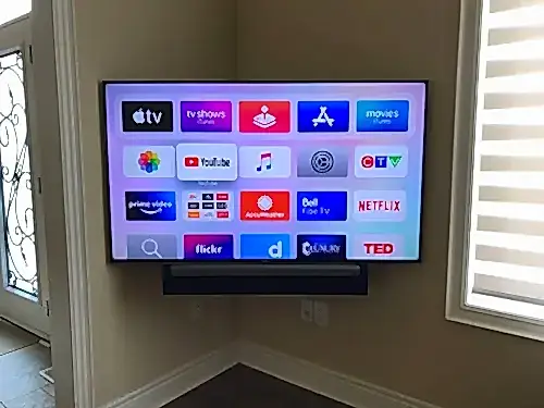 TV and soundbar mounted on an angled corner wall beside an entry door
