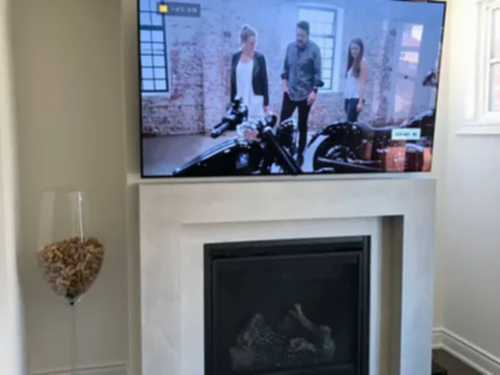 TV mounted above a cast stone mantel and gas fireplace in a bright living room