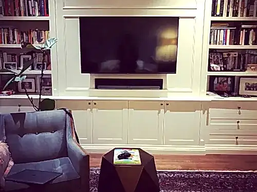 TV recessed into a white built-in bookcase wall, with a soundbar set into its own shelf recess below