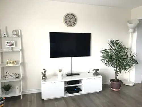 TV mounted on a cream wall with the cable run enclosed in a paintable raceway down to the console