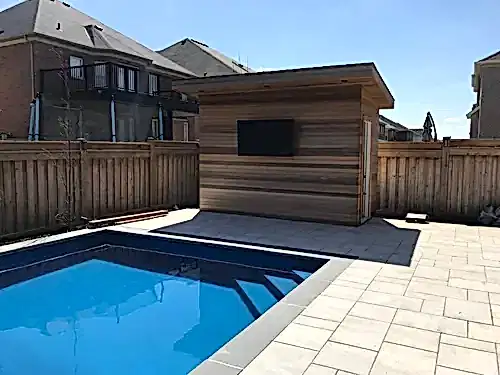 Outdoor TV mounted on the cedar-clad wall of a poolside cabana