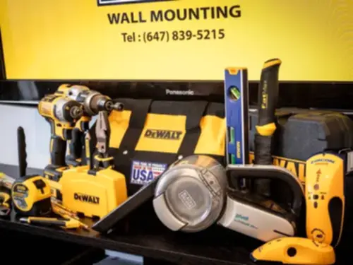 Drills, levels, a stud finder and a tool bag laid out in front of a screen showing the company logo