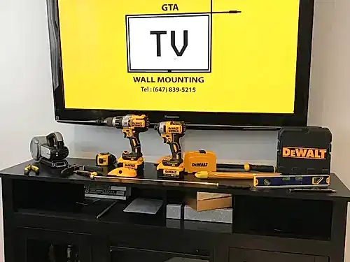 Cordless drills, a level and a stud finder set out in front of a screen showing the company logo
