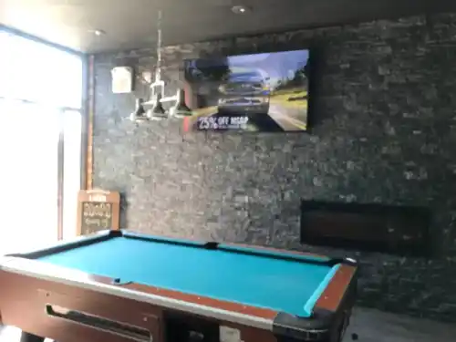TV mounted on a stacked stone bar wall above a linear fireplace, overlooking a pool table