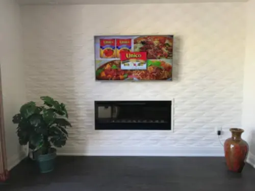 TV mounted on a white three-dimensional wave panel wall above a linear electric fireplace