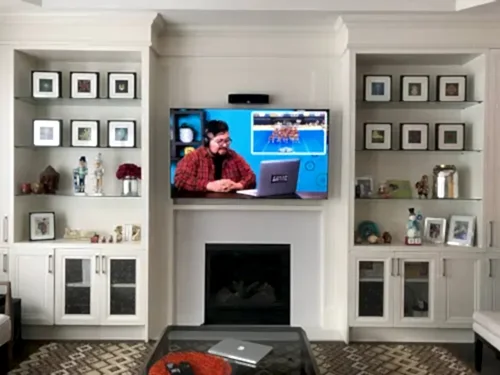 TV recessed into millwork above a traditional gas fireplace, between built-in display shelving