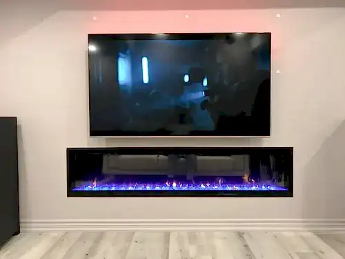 Large TV mounted above a long recessed linear electric fireplace, with cove lighting behind the screen