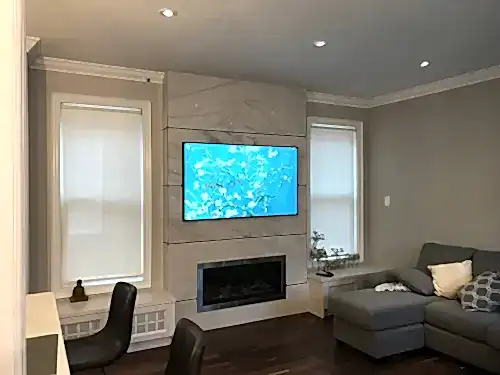 TV mounted on a marble slab panel above a linear fireplace in a family room with a sectional