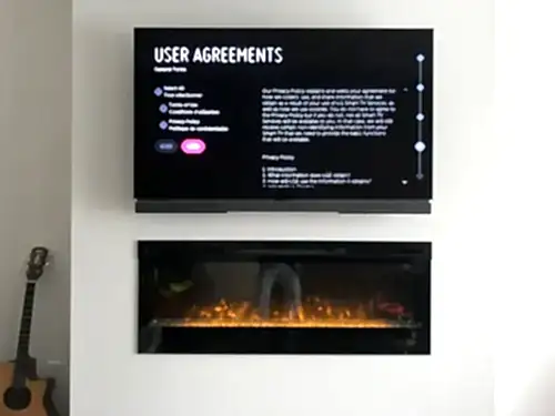 TV mounted above a wall-hung linear electric fireplace on a plain white wall