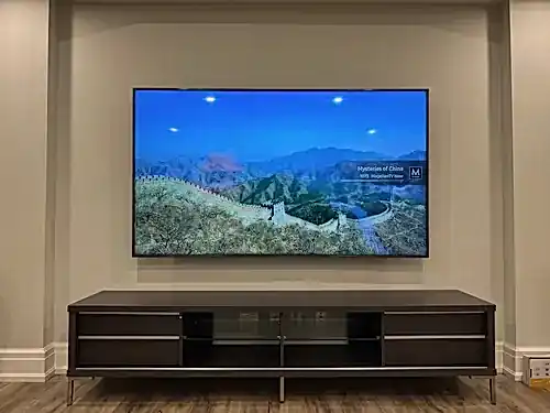 Large flat screen mounted inside a drywall alcove above a dark wood floating console in a finished basement