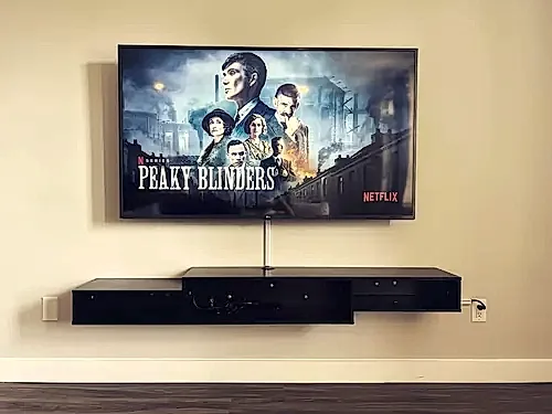 TV on a tilting mount above a black floating console, with the cables collected into a single channel below the screen