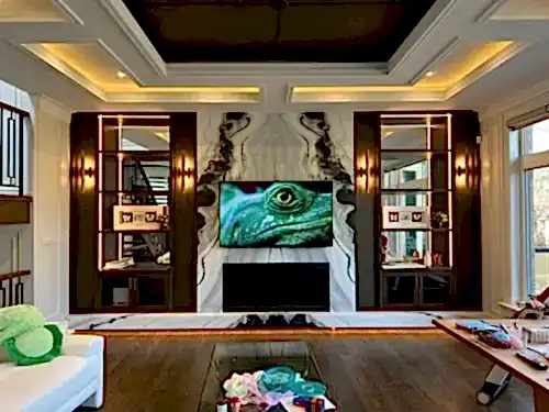 TV set into a marble feature wall between lit display cabinets, under a coffered ceiling with cove lighting