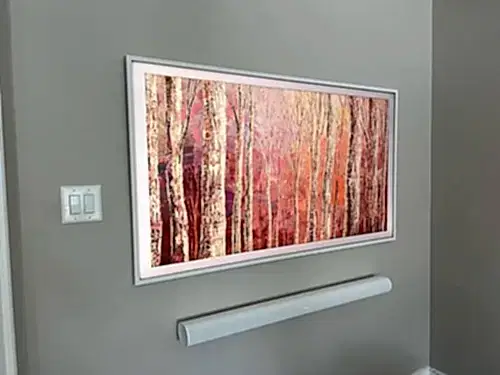 Angled view of a Samsung Frame TV sitting flush to a grey wall, showing how little the frame stands off