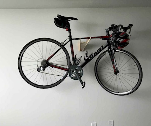 Road bike mounted horizontally on a wall bracket, helmet hanging off the handlebars