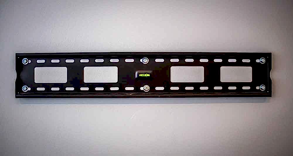 Basic tilting TV wall mount fitted flat to a wall with its long mounting plate visible