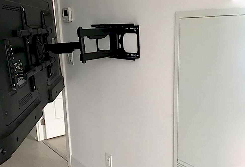 Double arm full motion TV wall mount holding a large flat screen angled away from the wall
