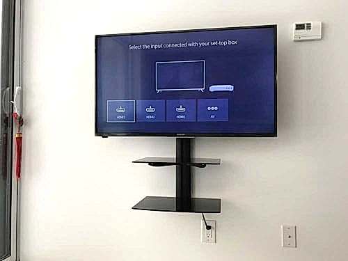 Two floating shelves installed on the wall below a mounted TV