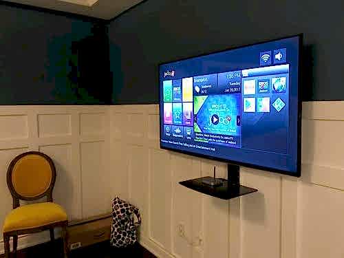 Single floating shelf installed on the wall below a mounted TV