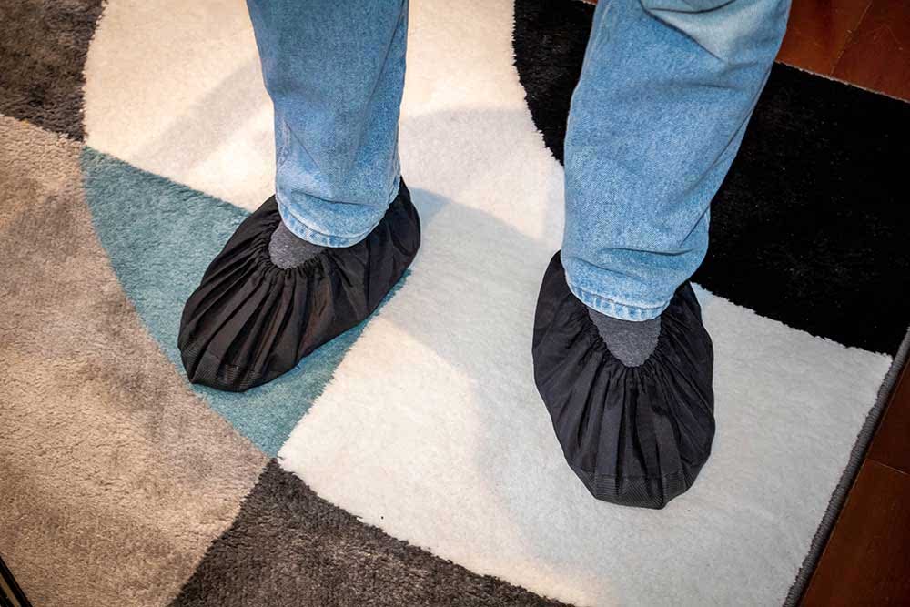 Installer putting on shoe covers at the door before starting a TV mounting job