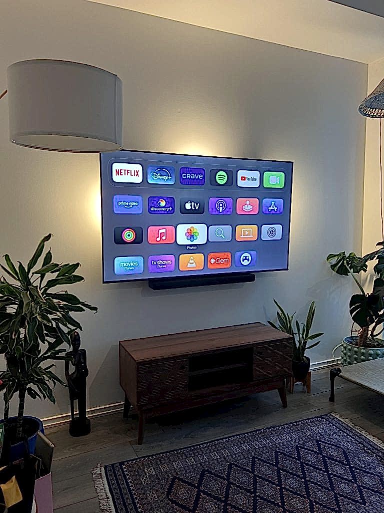 Slim soundbar fixed tight beneath a wall mounted TV in a living room